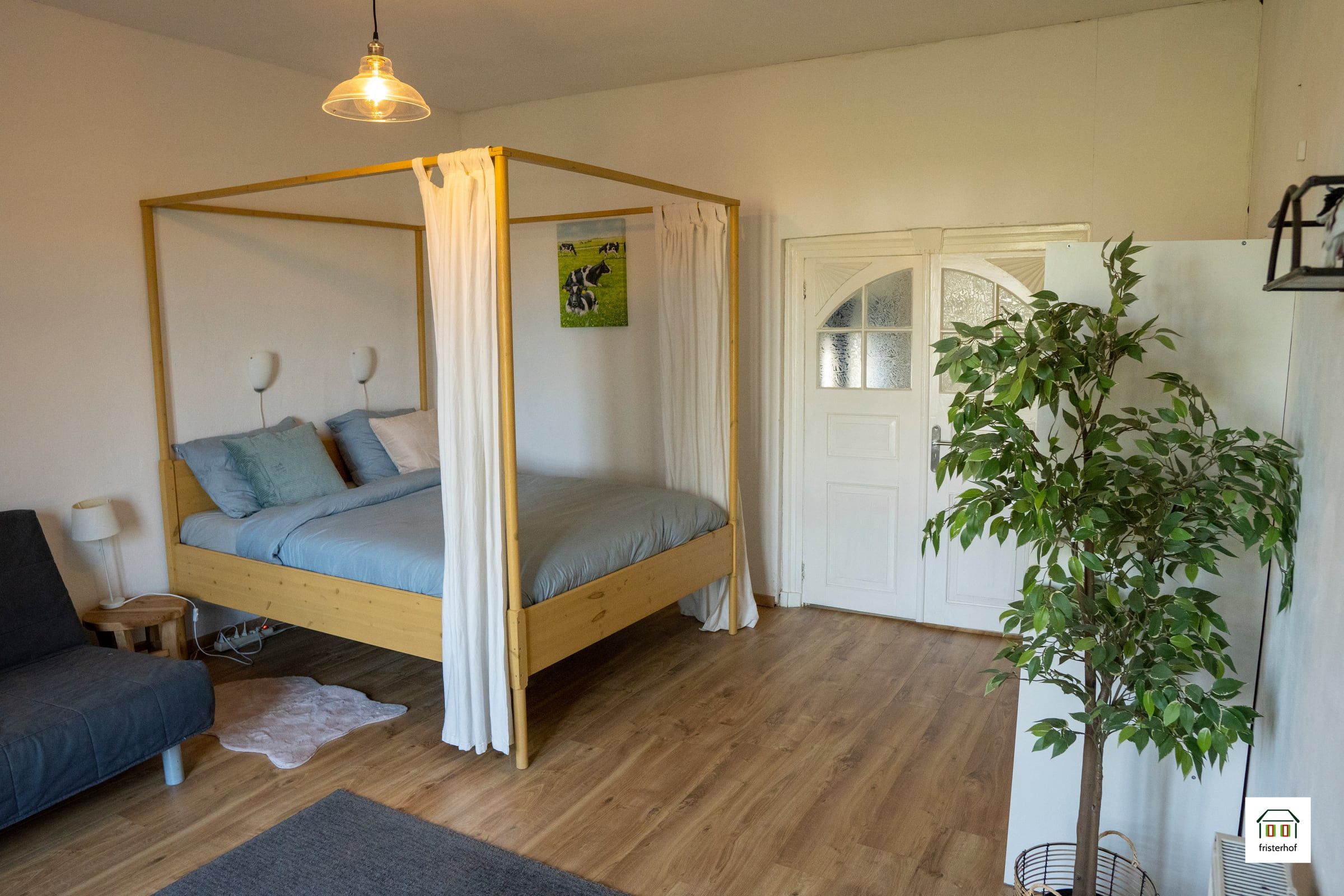 Schlafzimmer mit Himmelbett aus Holz und einem Schlafsofa