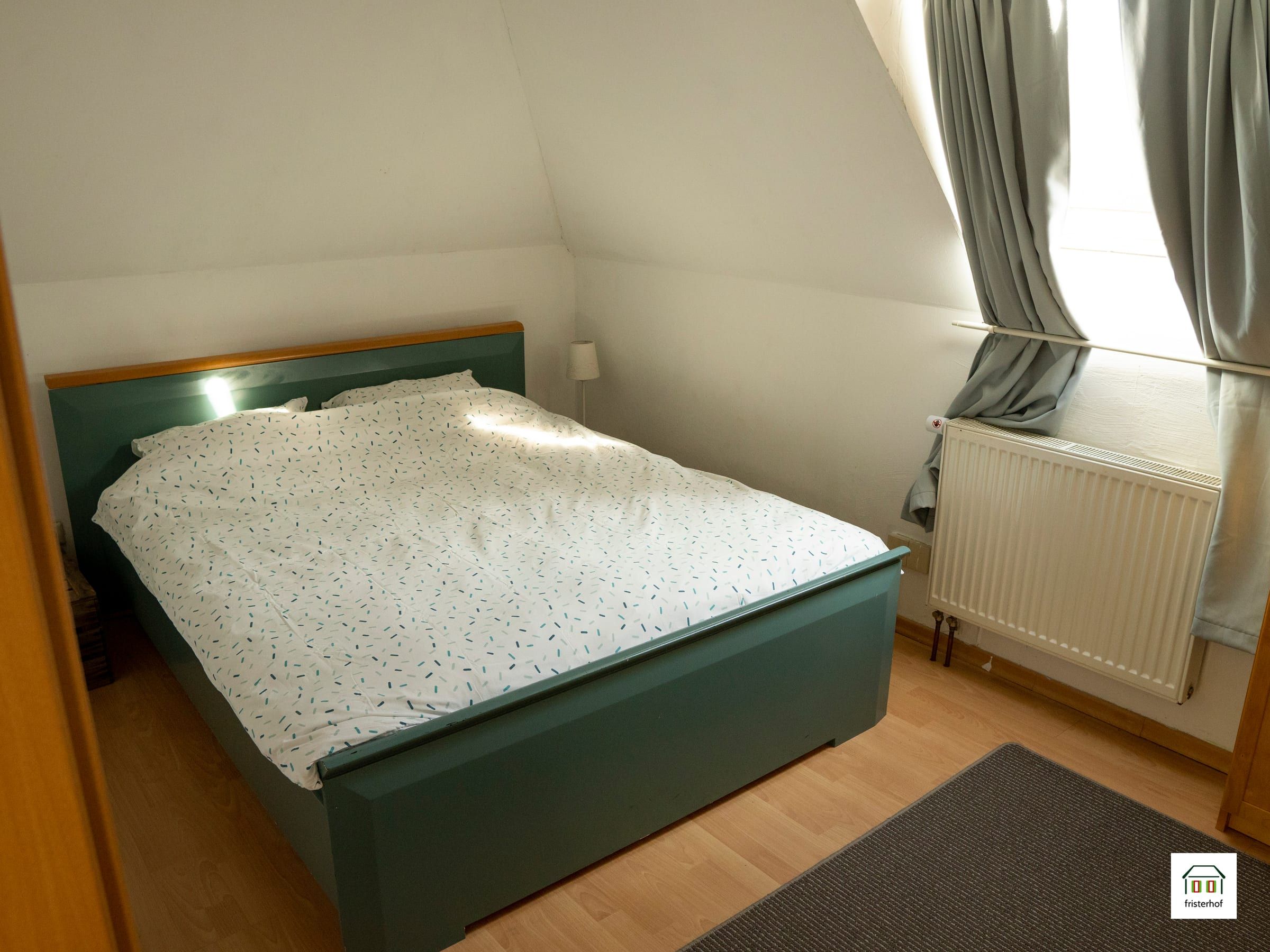 Schlafzimmer mit grünem Doppelbett unter einem Dachfenster