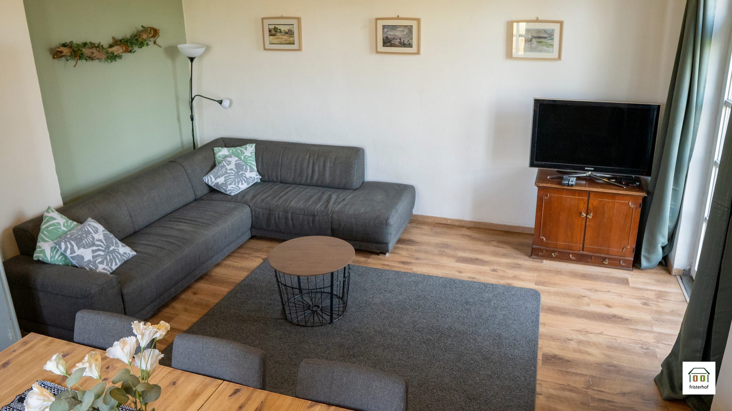 Wohnzimmer mit grauem Ecksofa, Couchtisch und Fernseher